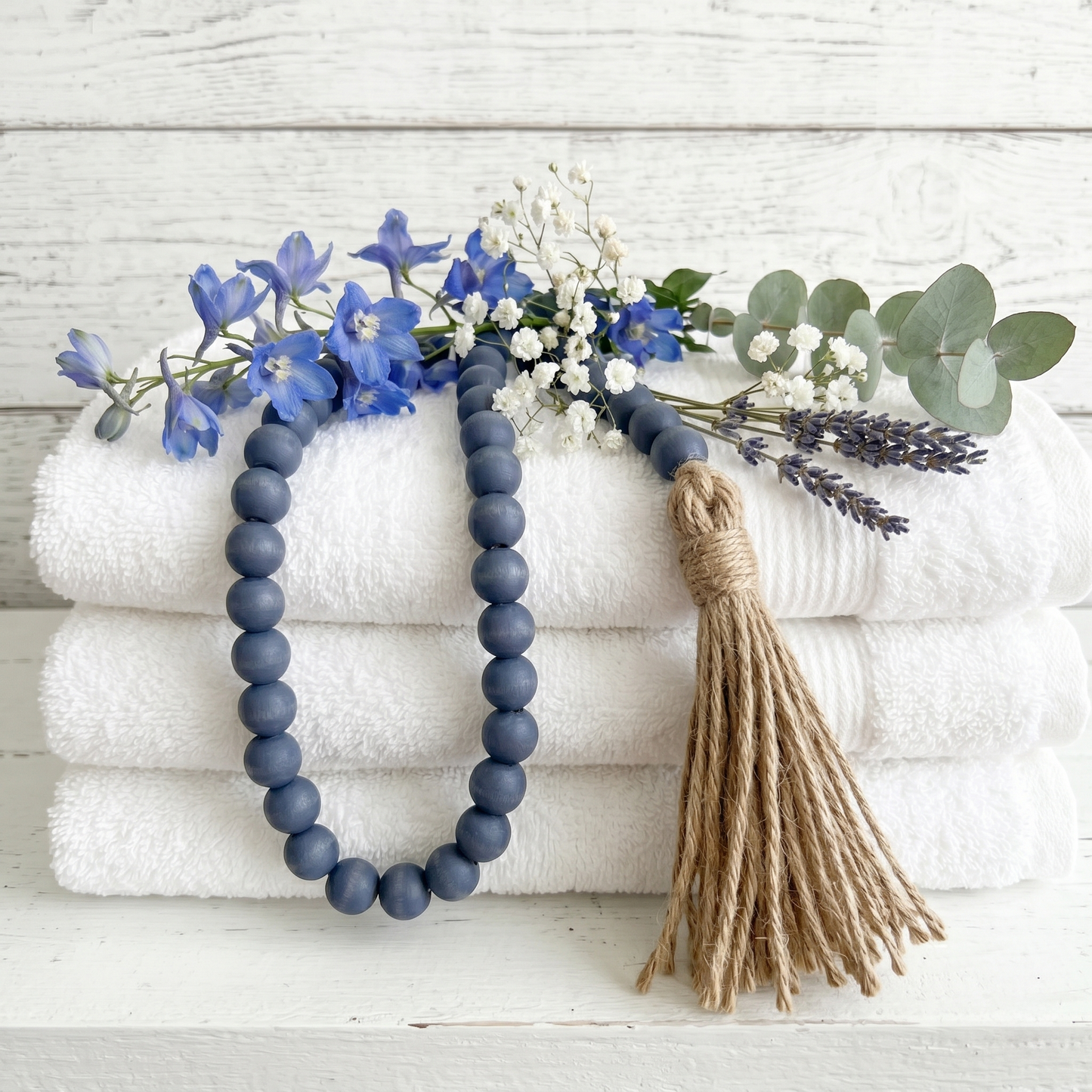 Navy Blue Wood Bead Garland (7) staged on towels and with flowers at rental property